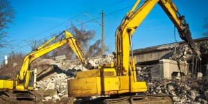 Two yellow excavators working near some powerlines
