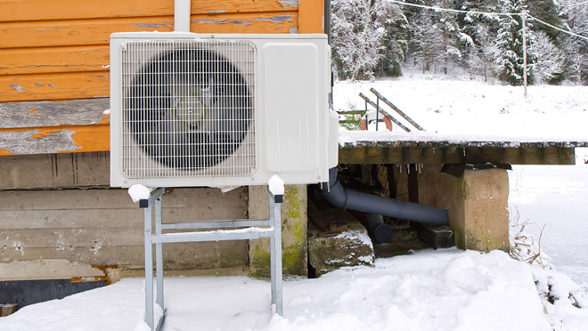 Winter view of a heat pump on the side of a rural home