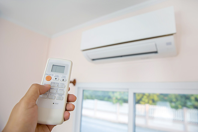 Image of a person using a remote control to set the temperature on a heat pump