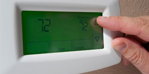 Person turning up a digital thermostat