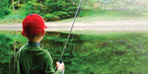 Boy fishing on a river lined with trees