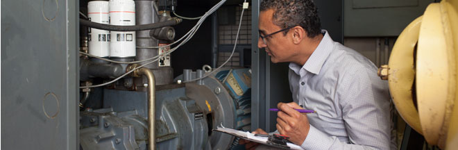 An engineer inspects an air compressor
