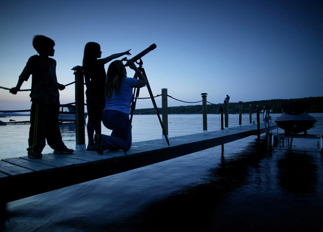 Family looking through a telescope on a dock full width Family looking through a telescope on a dock full width