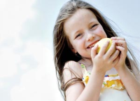 Young girl eating a pear with the sky in the background Young girl eating a pear with the sky in the background
