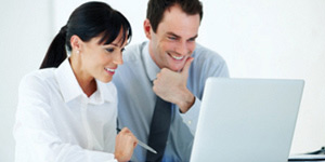 Two coworkers looking eagerly at a laptop