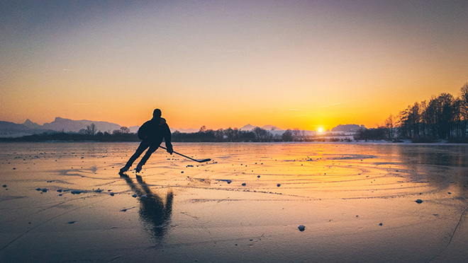 Hockey player on a frozen B.C. lake at sunrise