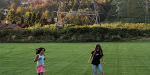 Young girls playing soccer on a field with transmission lines in the background