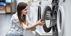 A young woman in a store chooses a washing machine