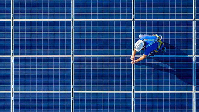 A worker on a rooftop solar panel array