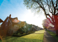 Row of residential houses with sidewalk, sky, and lens flare Row of residential houses with sidewalk, sky, and lens flare