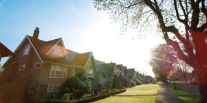 Row of residential houses with sidewalk, sky, and lens flare