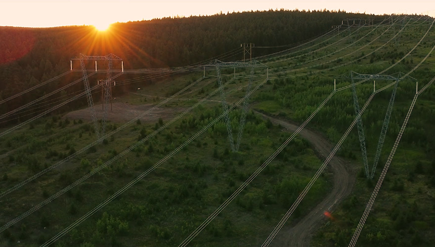 Aerial view of powerlines running across a grassy landscape at sunset