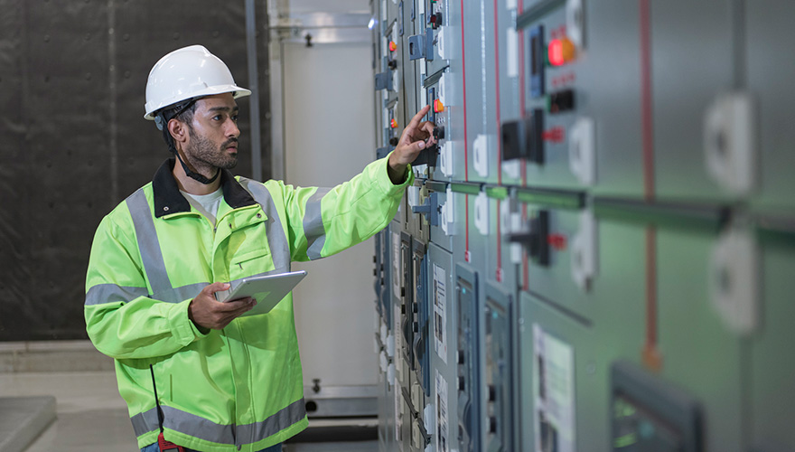 Worker inspects panel board in main distribution station room
