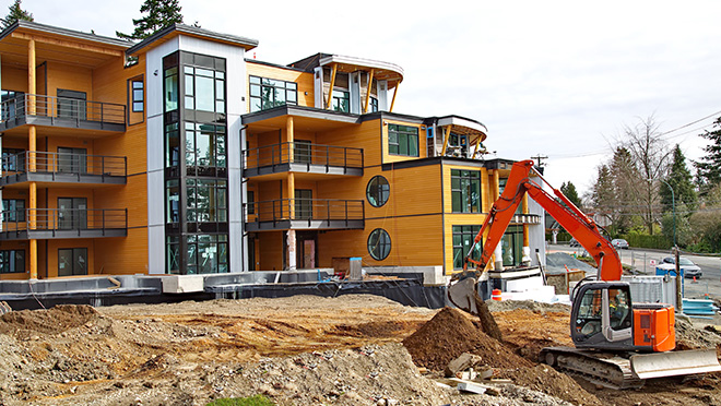 Construction of new apartment building. Crane in the foreground excavating soil.