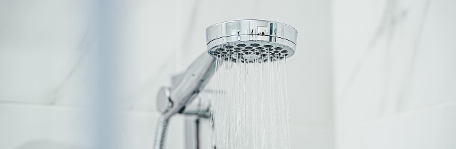 A modern chrome shower head with visible jets of water.