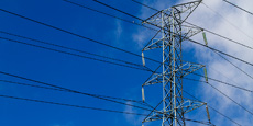 Transmission tower with numerous power lines, set against a clear blue sky.