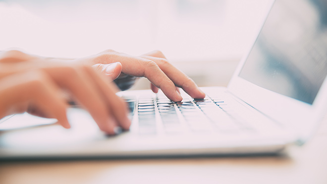 Image of hands typing on laptop keyboard