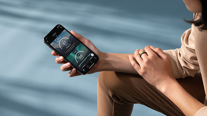 Woman with the Oura Ring  app showing real-time information to her smartphone.