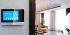 A smart home control panel mounted on a wall showing weather, date, and control icons.