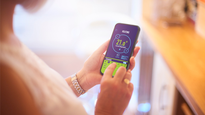 Image of a woman looking at a smart thermostat app on her phone