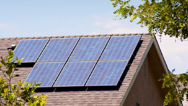 Solar panels installed on a sloped residential roof with clear sky and surrounding tree branches. Solar panels installed on a sloped residential roof with clear sky and surrounding tree branches.