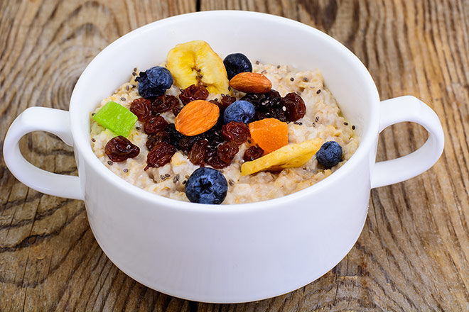 Oatmeal porridge with berries, banana and nuts in a bowl.
