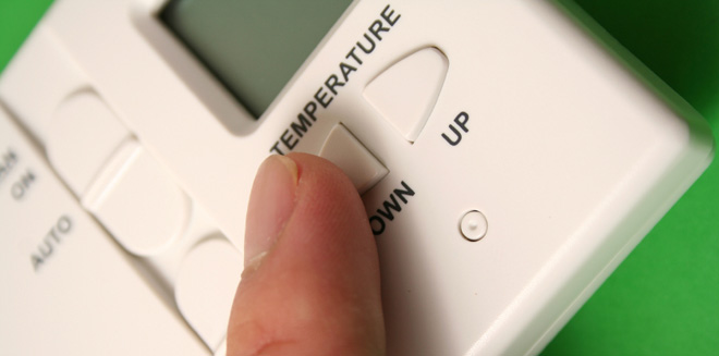 Finger adjusting temperature on digital thermostat Finger adjusting temperature on digital thermostat