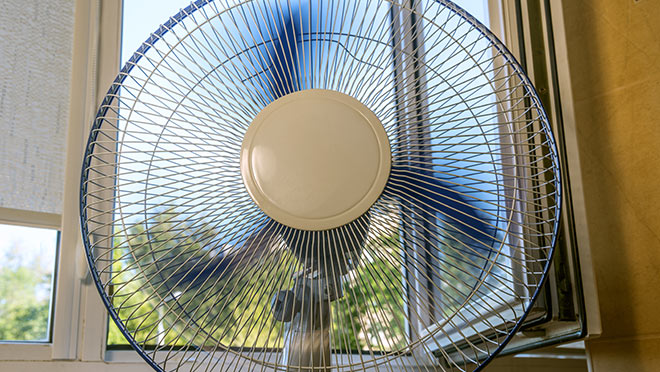 Image of a fan running in front of an open window