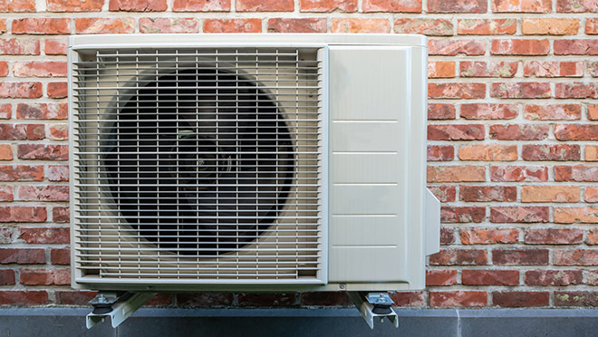Heat pump on the wall of a brick home