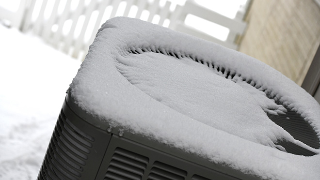 Heat pump covered in fresh winter snow