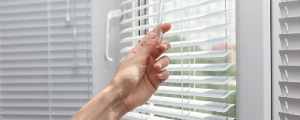 Photo of a person adjusting window blinds