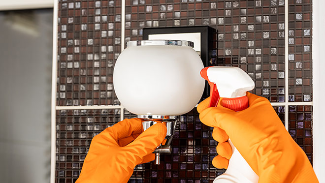 Image of a person cleaning a bathroom light fixture