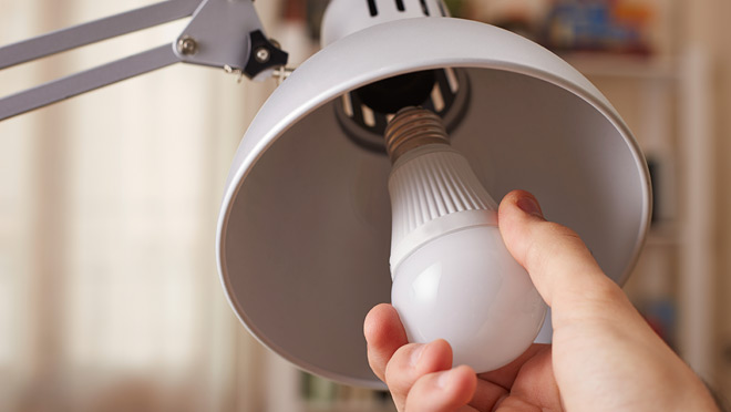 Image of a hand changing a regular light bulb for LED Image of a hand changing a regular light bulb for LED