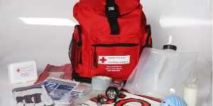 A red emergency kit backpack is surrounded by medical supplies. 
