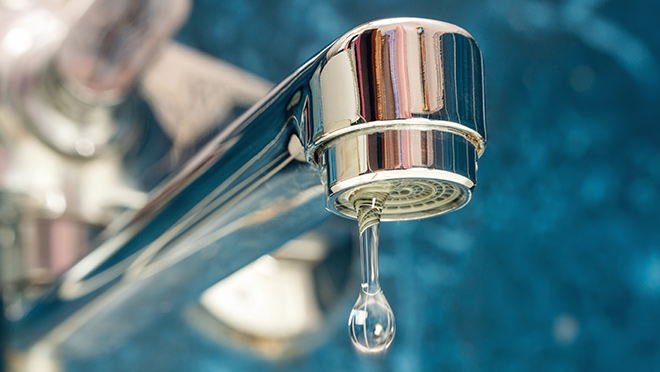 Water dripping from a shiny kitchen faucet