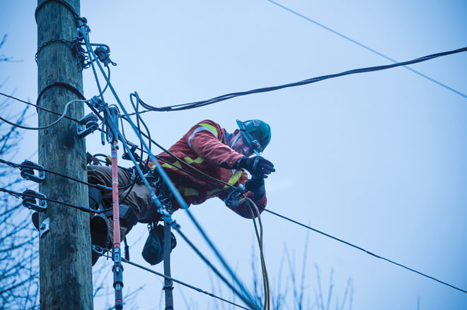 Power line technician on pole fixing cables
