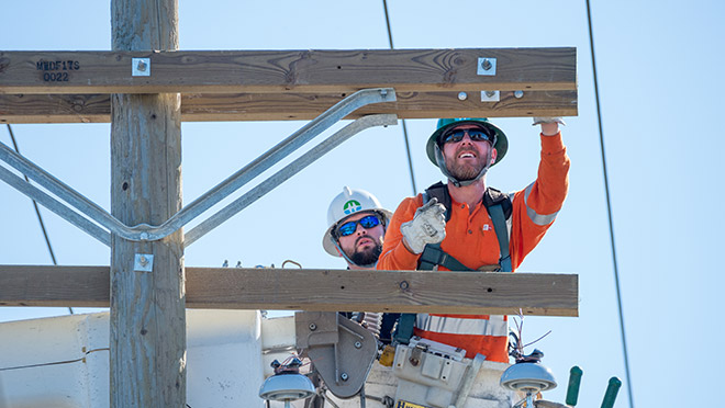 BC Hydro power line technicians work on a cross arm