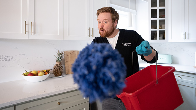 Dave with a bucket and duster, cleaning a kitchen