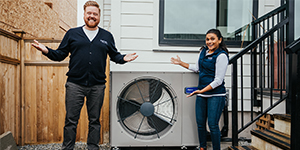 Dave & Jaclyn standing in front of a Heat Pump 