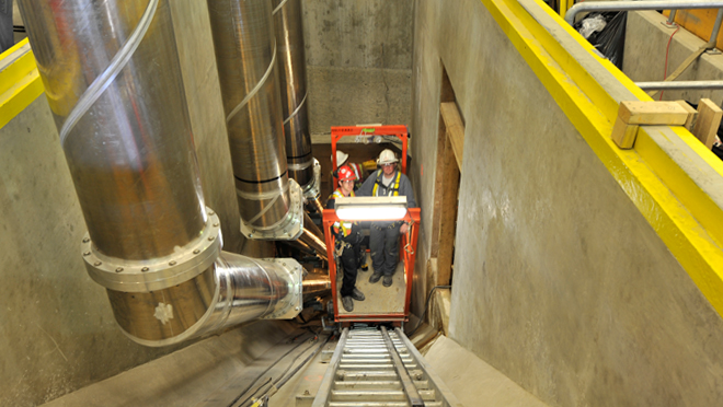 Crews use a cart on rails to transport through the tunnels. installing conductors in tunnels from the underground units of Mica. A small cart on rails was used to transport works up and down the tunnel.