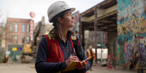 A technical person wearing a hard hat and vest checking a site.