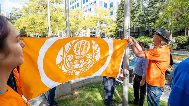 Members of BC Hydro's RAIN Network raising the Indigenous Survivors flag at BC Hydro's head office