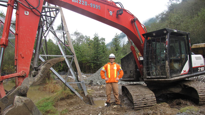 Trevor Scott standing at Indian River with the backhoe Trevor Scott standing at Indian River with the backhoe