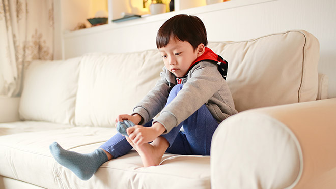 Young boy putting on socks