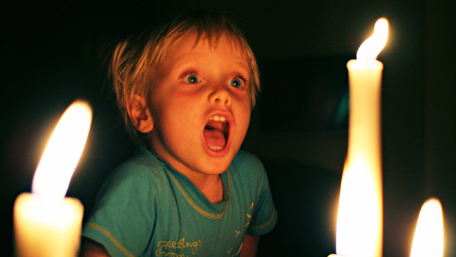 Child wide-eyed in candlelight Child wide-eyed in candlelight