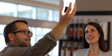 A contractor holds up a light bulb while interacting with the client behind the counter in a restaurant.
