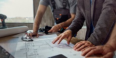 Close up of unrecognizable interior designer and manual workers cooperating while working on plans during home renovation process.