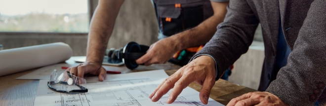 Contractors reviewing construction blueprints Contractors reviewing construction blueprints on a table a construction site.