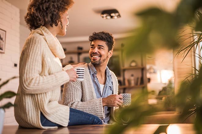 A happy couple drinks coffee while wearing warm sweaters