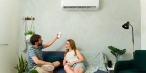 Couple in apartment adjusting heat pump.
